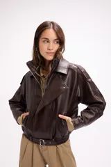 Campera estilo bomber oversize confeccionada en símil cuero color marrón oscuro. Presenta cuello solapa, cierre frontal, hombreras con detalle de broche y ruedo con elástico y cinto ajustable con hebilla metálica.