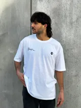 Remera blanca de corte oversize con estampado en la espalda que incluye dos círculos intersecados con las palabras 'Surf', 'Life' y 'Skate', y las frases 'Real Experience', 'Coexist' y 'Meaningful Day'.