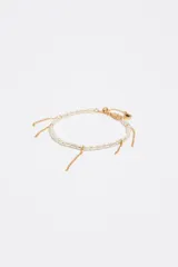 Pulsera dorada con perlas de resina y finas cadenas colgantes, con cierre de mosquetón ajustable y dije de corazón esmaltado.