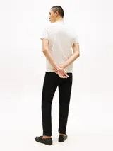 Remera de algodón color crema con cuello redondo y logo de Tommy Hilfiger bordado en el pecho. Tiene una pequeña bandera de la marca bordada en la manga izquierda.