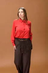 Camisa de manga larga color rojo, con cuello clásico y cierre frontal de botones. Presenta un diseño de corte recto y tejido con caída fluida.