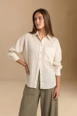 Camisa de manga larga con patrón de rayas sutiles, corte holgado, cuello camisero, cierre frontal con botones y un bolsillo aplicado en el pecho.
