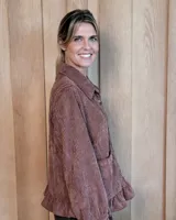 Sobrecamisa de pana color marrón oscuro, con cuello camisero, cierre frontal de botones y detalle de volado en el ruedo. Presenta mangas largas con puños y bolsillos frontales aplicados.