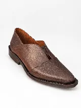 Mocasines de charol color bordó, de diseño vanguardista con corte asimétrico en el empeine, abertura en V, punta fina y suela plana con pequeño tacón.