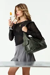 Cartera tipo hobo de cuero vegano color verde musgo, con diseño de tapa frontal, bolsillos laterales con solapa y cierre principal. Incluye correa corta para el hombro y correa regulable extraíble.