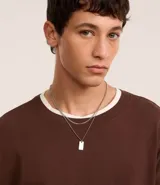 Collar doble dorado con cadena fina y dije rectangular.