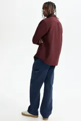 Camisa de algodón Oxford con cuello americano, tapeta clásica, bolsillo superior abierto y canesú en la espalda. Mangas largas con puños abotonados y bajo levemente redondeado.