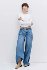 Jean de corte wide leg en color azul medio, con diseño de tiro alto y cierre frontal con botón y cremallera.