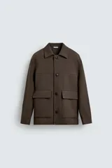 Chaquetón de corte regular fit en color marrón oscuro, con cuello solapa, manga larga y cierre frontal de botones. Presenta dos bolsillos de plastrón con solapa en la parte delantera.