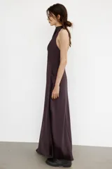 Vestido largo de satén negro con cuello halter y escote fluido. Presenta cierre con cremallera oculta en la espalda y lazada en el cuello.