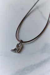 Dije de acero quirúrgico con forma de bota de estilo cowboy, con detalles grabados en relieve.