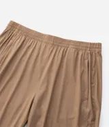 Pantalón deportivo de corte recto, color marrón, con cintura elástica y cordón de ajuste. Presenta bolsillos laterales con cierre y un diseño minimalista de tejido técnico.