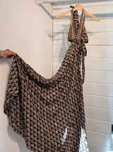 Vestido largo con estampado de hojas en tonos verde y blanco, con escote halter y espalda descubierta.