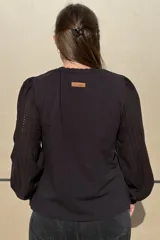 Remera de algodón color azul marino, con cuello redondo fruncido y mangas largas abullonadas con puños elásticos.