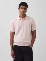 Buzo de punto de manga corta con cuello polo y cierre frontal de tres botones, en color rosado.