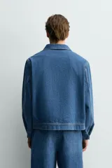 Cazadora de denim de algodón con cierre frontal de cremallera, cuello solapa y un bolsillo plastrón en el pecho. Presenta un diseño de corte regular con efecto lavado.