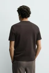 Camiseta de manga corta con cuello panadero y cierre frontal de tres botones. Presenta una textura acanalada y un corte regular fit.