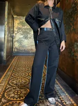 Pantalón negro de corte recto con detalle de franja celeste en el lateral.