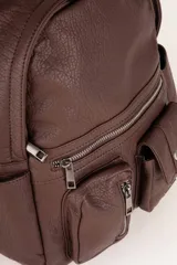 Mochila negra de símil cuero texturizado con tres bolsillos externos con cierre, dos bolsillos laterales, un asa fija y dos correas regulables.