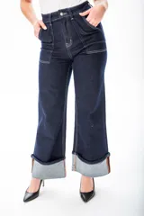 Pantalón de jean azul oscuro de corte ancho, con cintura alta, bolsillos delanteros y traseros con costuras blancas a contraste, y dobladillo ancho.