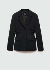 Blazer entallado de color negro con cuello de solapa, cierre frontal de tres botones y bolsillos delanteros con solapa. Presenta un diseño estructurado con detalles fruncidos en los laterales y forro interior.