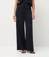 Pantalón de corte wide leg confeccionado en tejido punto roma, con diseño de raya de tiza, cintura estructurada, bolsillos delanteros y cierre frontal discreto.