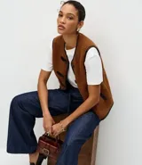Pantalón de jean corte wide leg en color azul oscuro, con cintura alta, cierre frontal con botón y cremallera, y cinturón de lazo del mismo tejido.