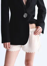 Short mini de viscosa semitransparente color crudo, con diseño bordado, bajo festoneado y cintura ajustable con elástico en los laterales.
