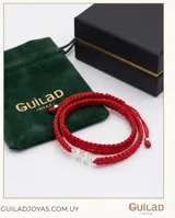 Pulsera de hilo rojo tejida en macramé con dije central de dos figuras de niños en plata 925 y terminaciones con esferas de plata. Diseño ajustable.