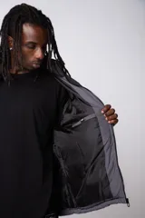 Campera puffer de diseño bicolor, con cuerpo en tono beige y canesú superior en color negro. Presenta cuello alto, cierre frontal completo y puños elásticos.