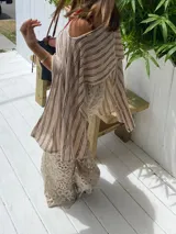 Poncho de tejido de punto, color crudo con rayas horizontales negras. Diseño holgado y asimétrico, con escote amplio.