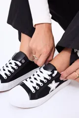Championes de lona color negro con puntera y cordones blancos, presentan un detalle de estrella blanca en el lateral.