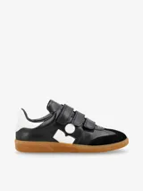 Zapatillas de cuero negro con detalles en blanco, cierre con tres tiras de velcro y suela de goma color caramelo.