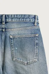 Jeans flare fit de denim de algodón en color celeste con lavado efecto desgastado. Presentan diseño de cinco bolsillos, tiro medio, cierre frontal con cremallera y botón, y bajo con acabado irregular.