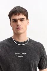 Remera de algodón color marrón con efecto gastado, de manga corta, cuello redondo y estampa tipográfica sutil al frente.