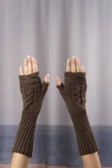 Guantes mitones largos de tejido de punto artesanal, color marrón, con diseño de trenzas y textura acanalada en el antebrazo. Presentan un diseño sin dedos para mayor movilidad.