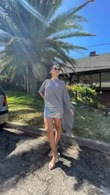 Vestido corto de dos piezas compuesto por una base strapless con frunces y acabado satinado, acompañada de una capa transparente desmontable de corte asimétrico.