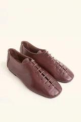 Zapatos chatos de cuero color bordó, con cordones finos y punta cuadrada.