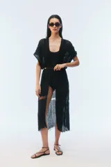 Kimono largo de algodón negro con punto calado, calce amplio, hombros caídos, mangas cortas, aberturas laterales y terminación desflecada en el ruedo.