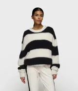 Suéter corto de punto grueso y peludo, con rayas horizontales anchas en blanco roto y negro. Presenta cuello redondo y mangas largas con puños anchos.