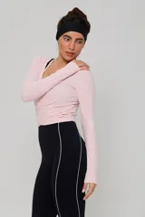 Top deportivo de manga larga en color rosa claro, con diseño cruzado tipo ballet y escote en V. Confeccionado en tejido elástico y ligero.