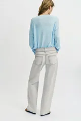 Jeans de corte recto y tiro bajo, confeccionados en tejido de algodón. Presentan diseño de cinco bolsillos, cierre frontal con cremallera y botones, y detalle de cinturón integrado en la cintura.