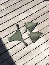 Conjunto de bikini color verde oliva con textura acanalada. El top es de estilo triangular con breteles regulables y cierre de gancho en la espalda. La bombacha es de corte vedetina con laterales fruncidos elásticos.