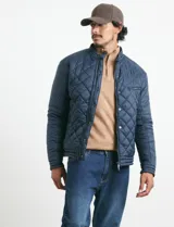 Campera capitoneada de color azul oscuro, con cierre frontal de metal y botones a presión. Presenta bolsillos laterales y en el pecho con cierres metálicos.