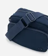 Cartera bandolera de tamaño pequeño, confeccionada en poliéster con estructura ligeramente acolchada. Cuenta con un bolsillo delantero con cierre, compartimento principal con cierre doble y correa ajustable.
