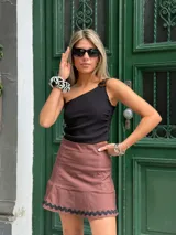 Musculosa negra de un hombro con hebilla carey y frunce en la parte delantera.