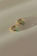 Aros de acero quirúrgico dorados en forma de argolla con dijes de piedra natural negra en forma de dona, desmontables.