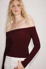 Jersey de punto color bordó, con escote barco de hombros descubiertos y manga larga.