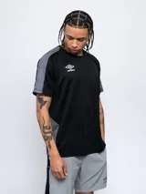 Remera deportiva Umbro de manga corta, color azul marino con detalles en azul claro en los hombros y laterales. Presenta cuello redondo y logo de la marca estampado en el pecho.