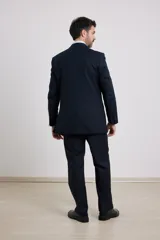 Traje de corte clásico compuesto por saco de dos botones y pantalón de vestir a juego. El saco presenta solapas tradicionales y bolsillos con solapa, mientras que el pantalón tiene un corte recto y formal.